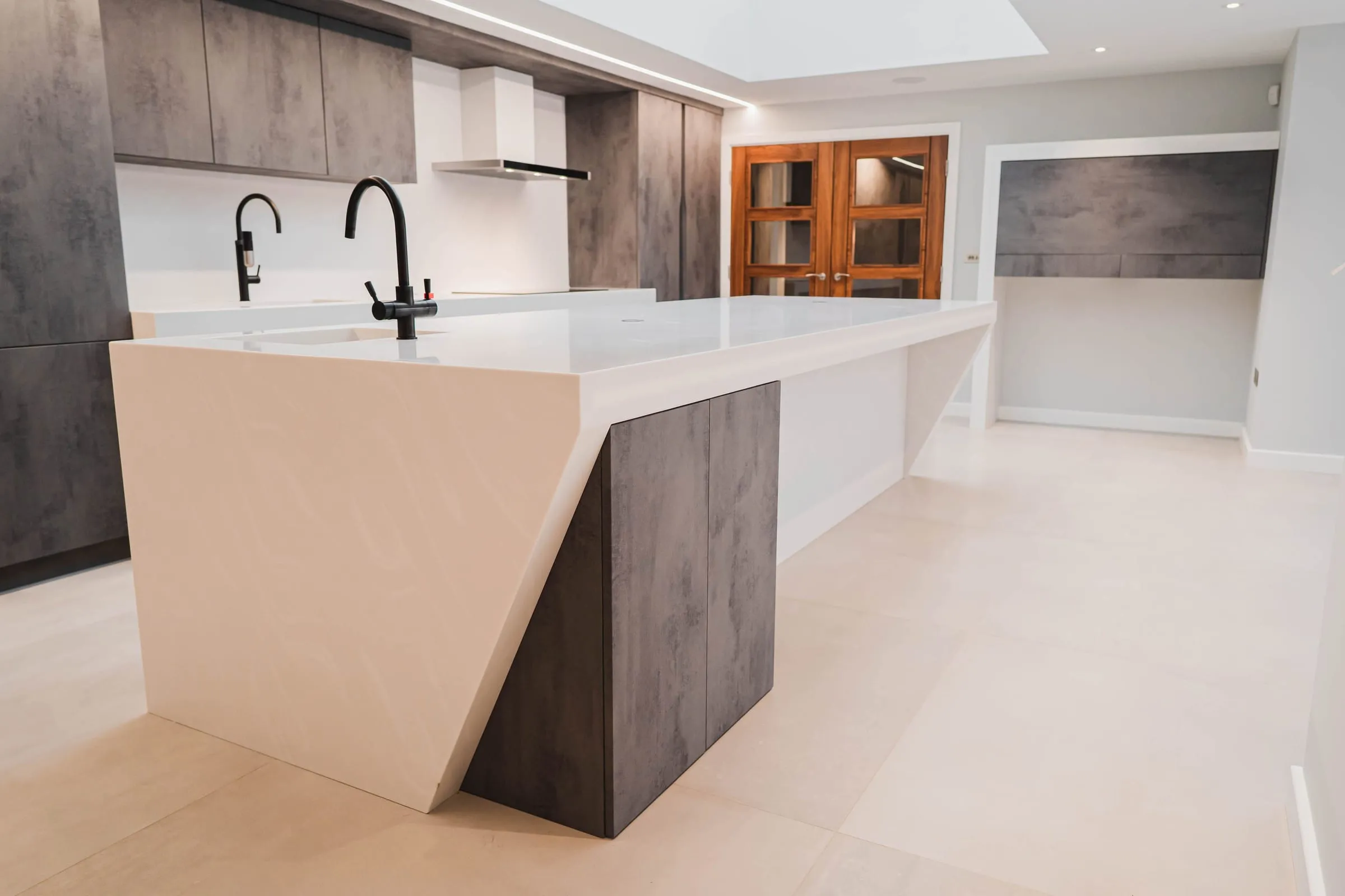Angular white kitchen island with a dark concrete-effect end panel