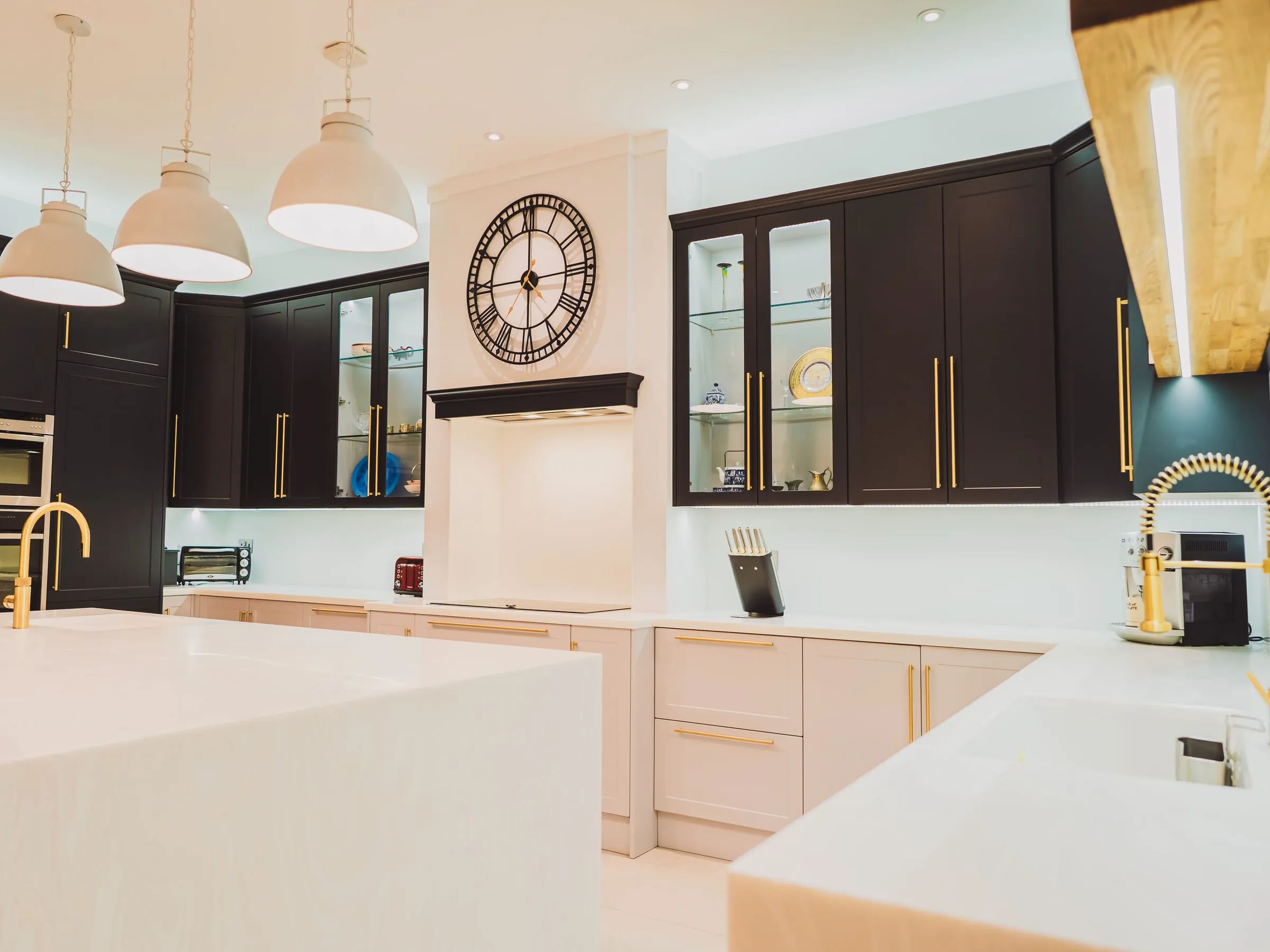 Dark blue fitted kitchen with glazed cabinets and a large wall clock