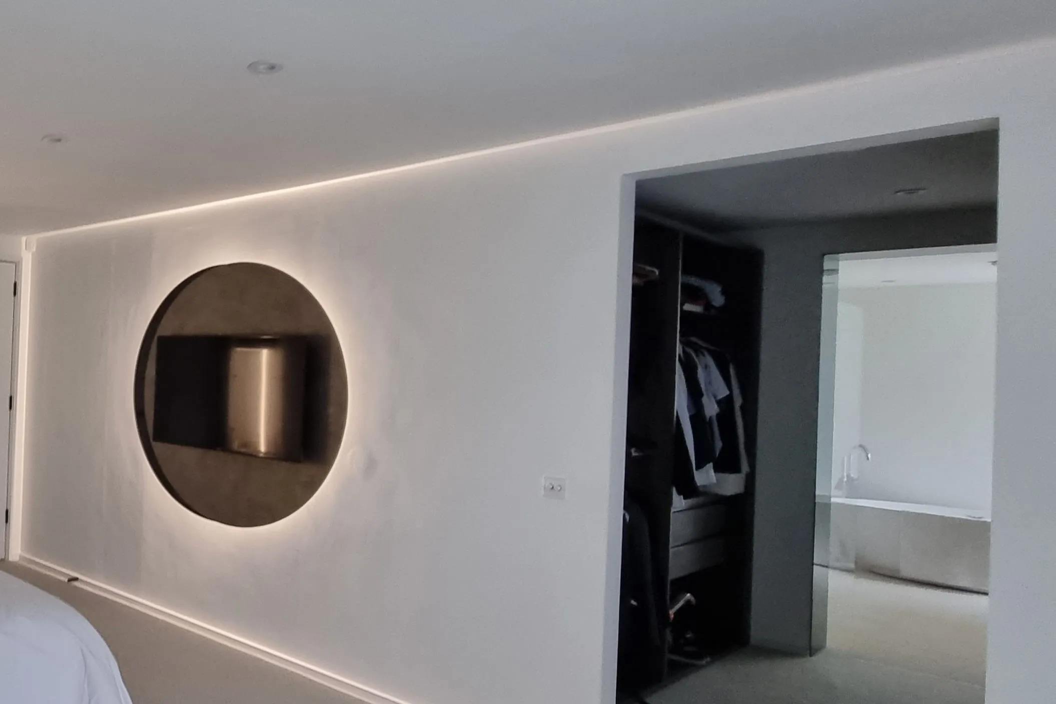 Bedroom wall with a circular TV feature and a walk-in wardrobe doorway