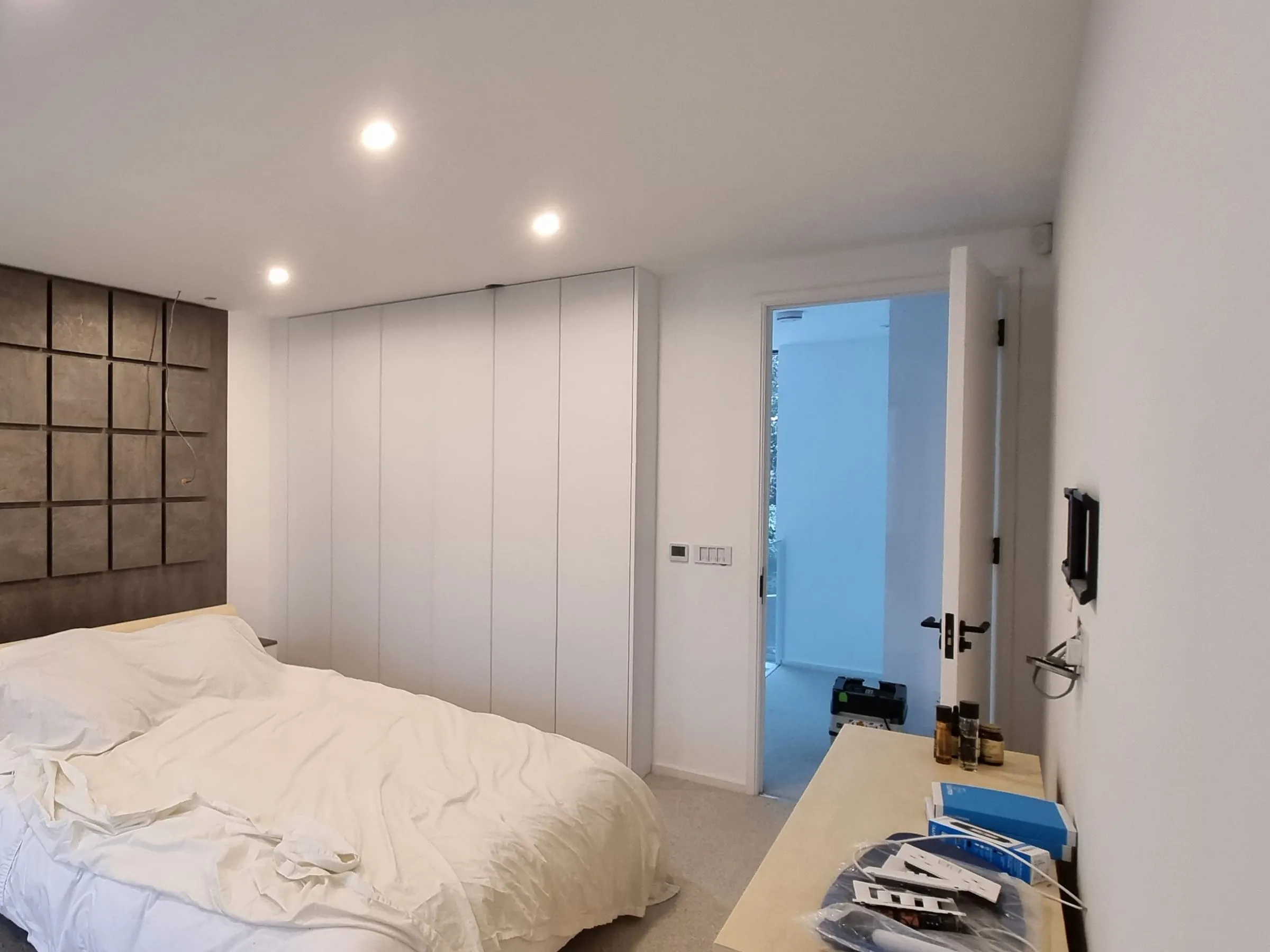 White handleless wardrobes beside a panelled headboard wall