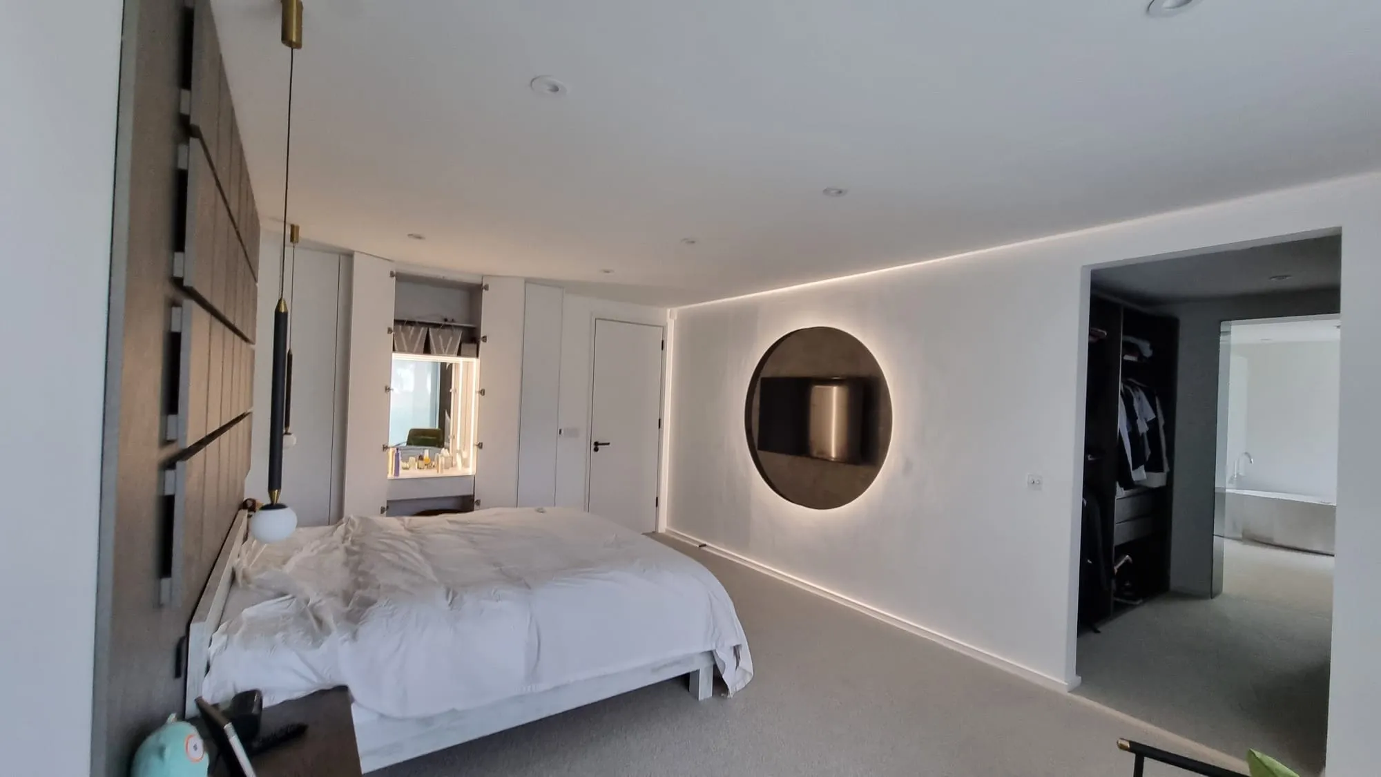 Modern bedroom with built-in wardrobes, a circular TV feature and a walk-in wardrobe doorway