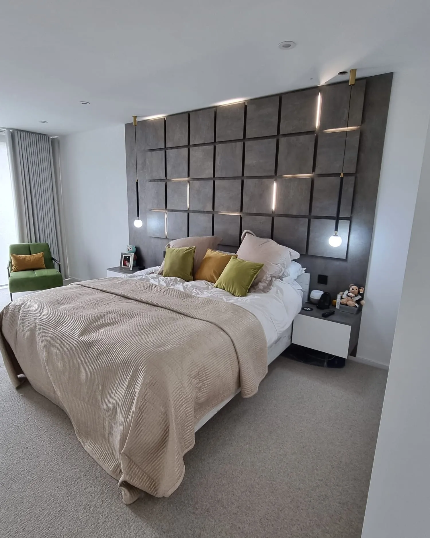 Made-up bed against a padded panel headboard wall in a fitted bedroom