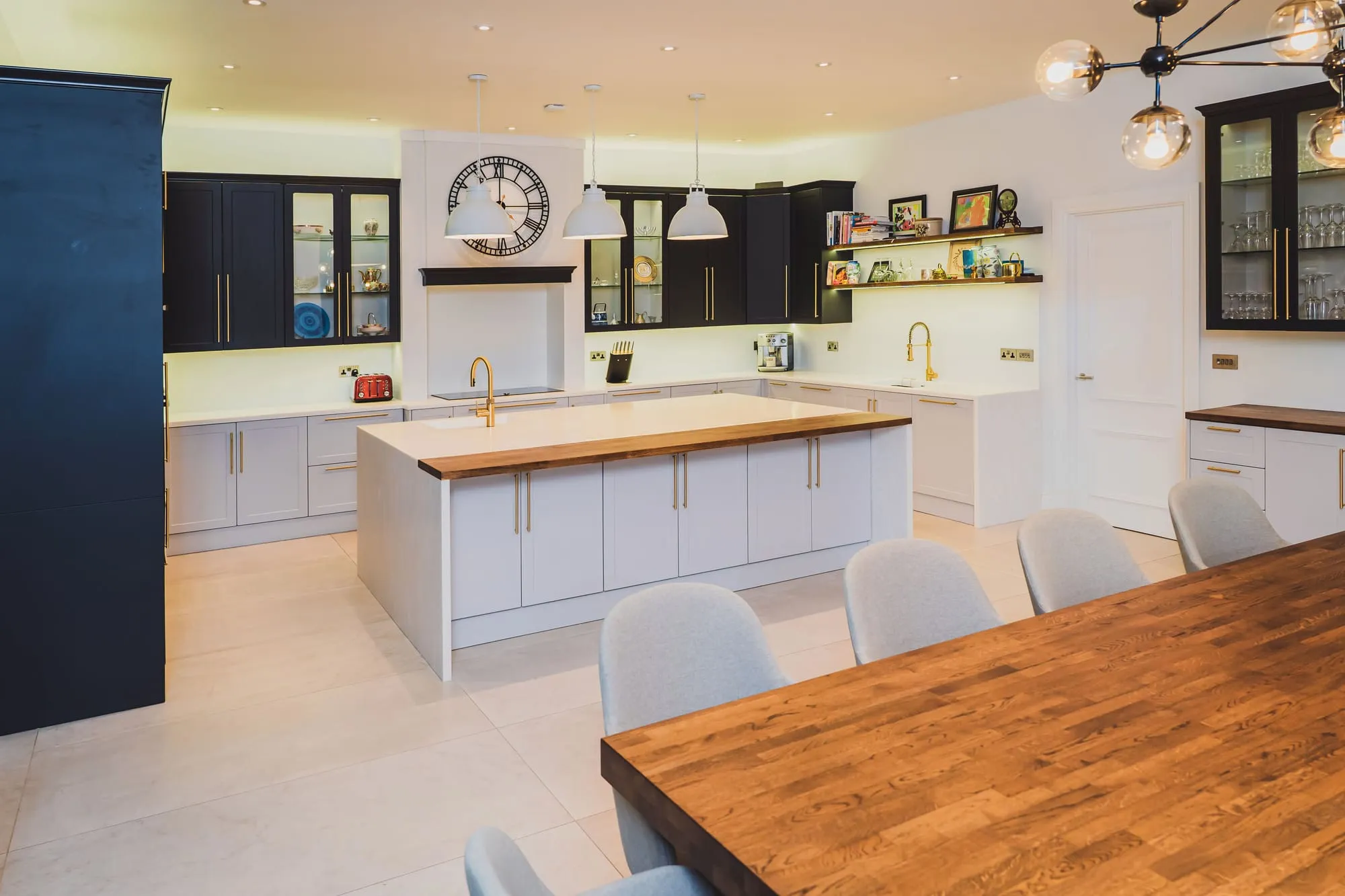 Navy and white shaker kitchen with brass fittings and an oak dining table
