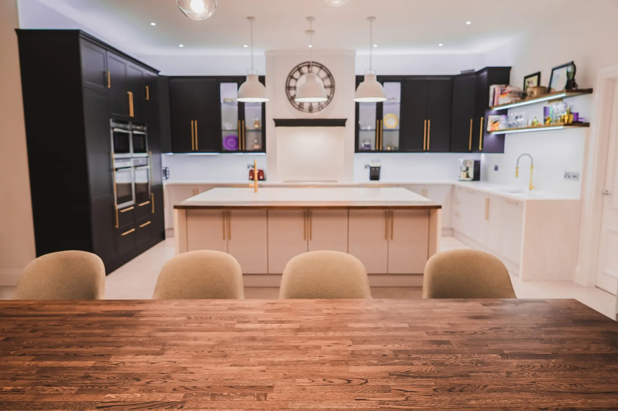 Navy fitted kitchen with glazed cabinets seen across an oak table