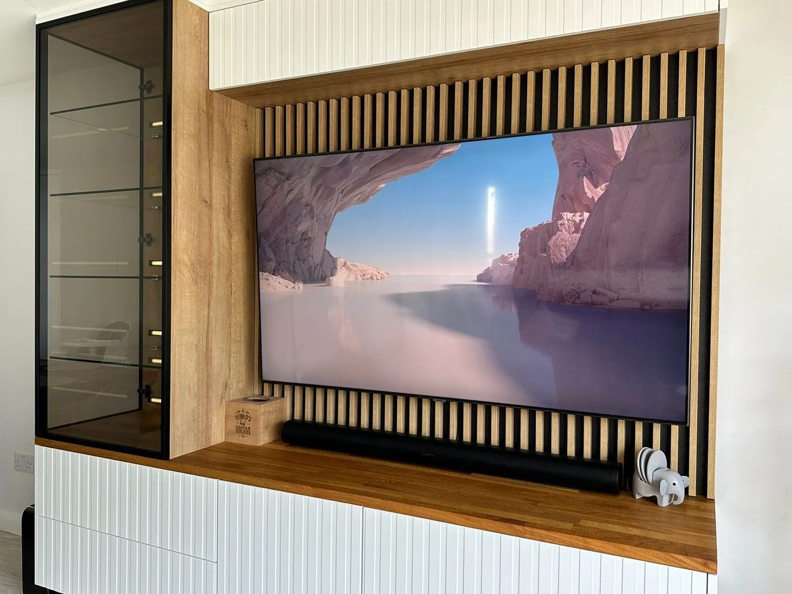 Oak slatted media wall with a TV and a built-in glass display cabinet