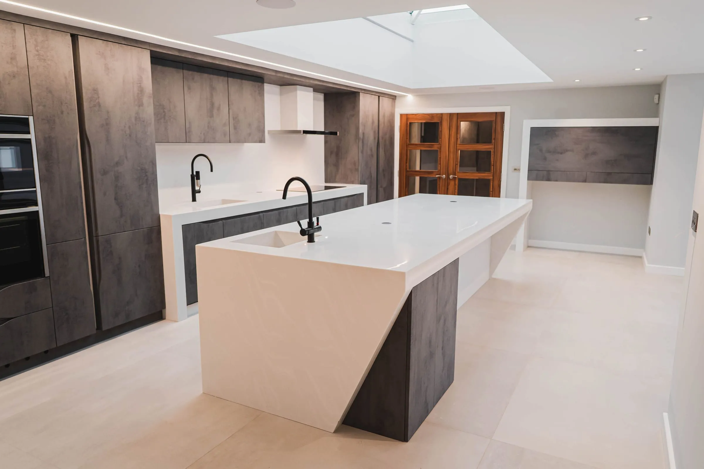 Sculptural white kitchen island with a concrete-effect base, seen from the side