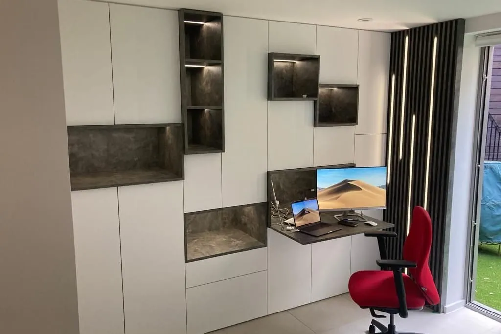 White handleless office cabinets with an integrated desk and slatted panel
