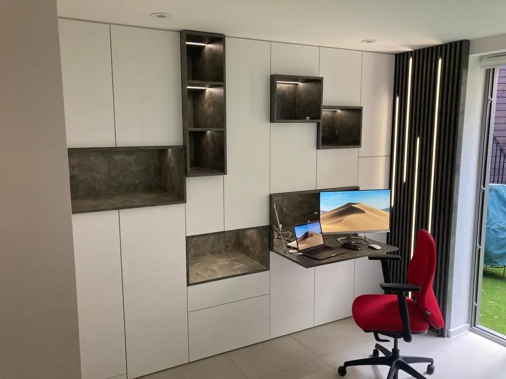 Home office wall unit with a fold-down desk, stone-effect niches and lit shelves