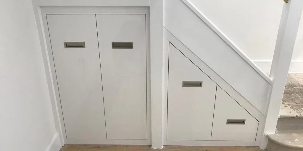 Under stairs storage with flush white doors and drawers set into the staircase